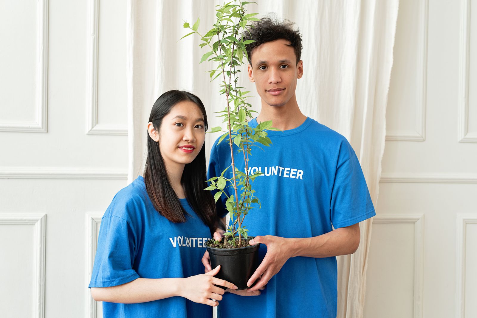 Deux jeunes bénévoles tiennent une plante en pot